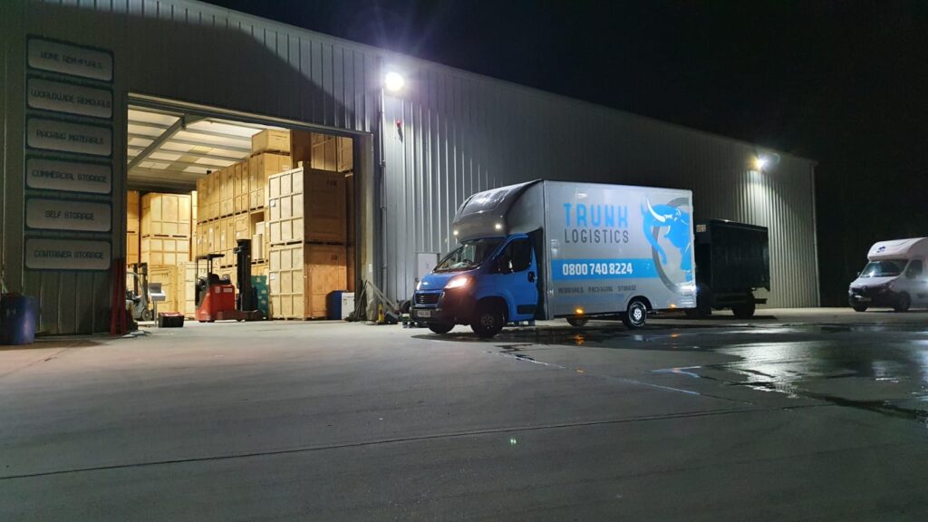 Two-person collection and delivery storage service van at secure Trunk Logistics warehouse in Essex at night