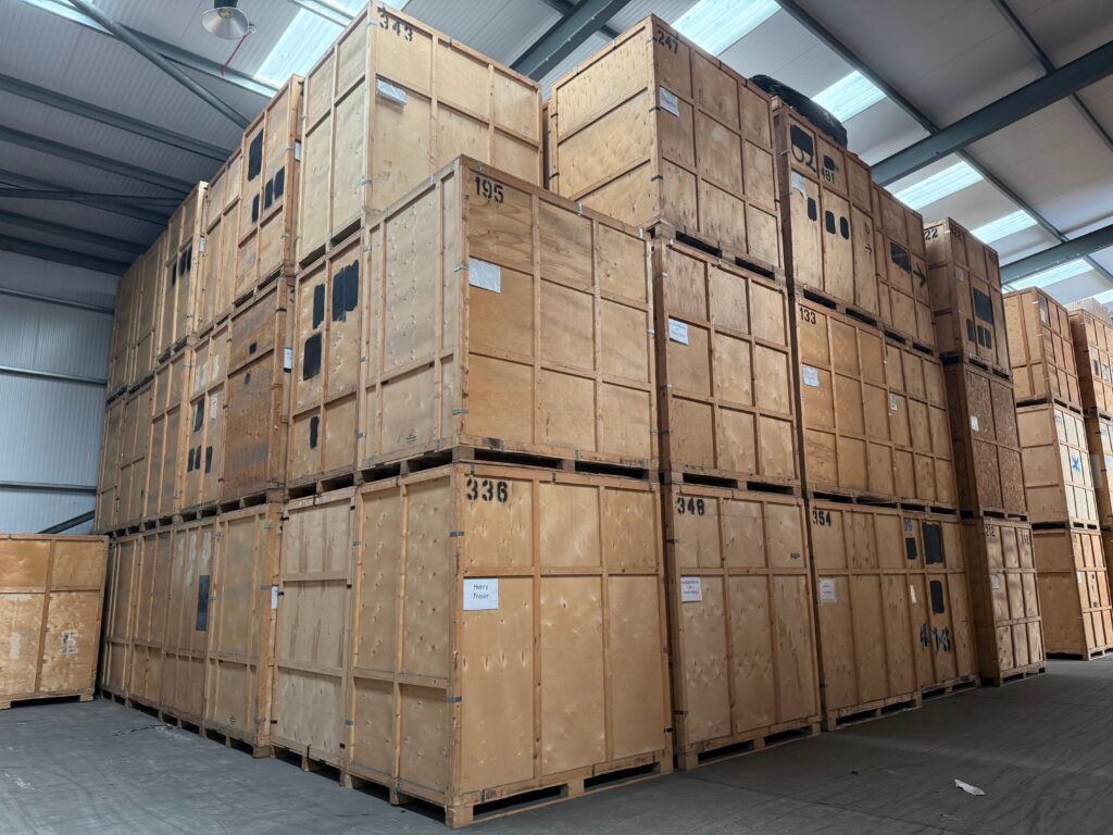 Stacked wooden student storage crates in secure UK warehouse