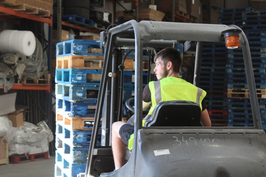 Hotel Clearance and Defit Service Trunk Logistics forklift operator in high visibility vest operating forklift in commercial warehouse in Essex with racked pallet storage