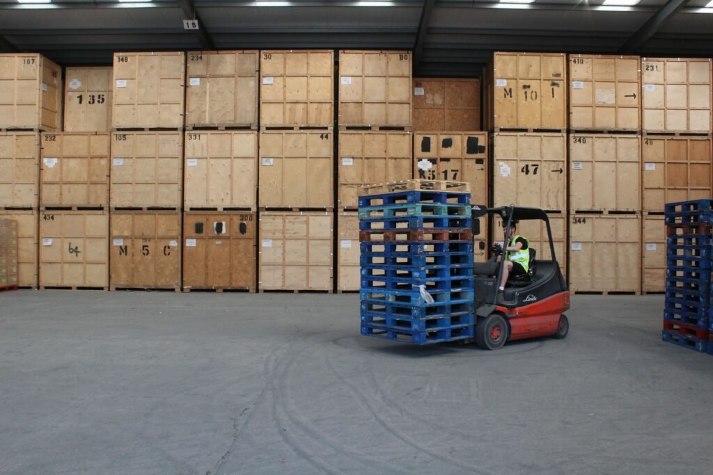 Machinery Pre-Site Storage Forklift operating in Trunk Logistics warehouse in Essex moving pallets in front of wall of numbered wooden storage crates