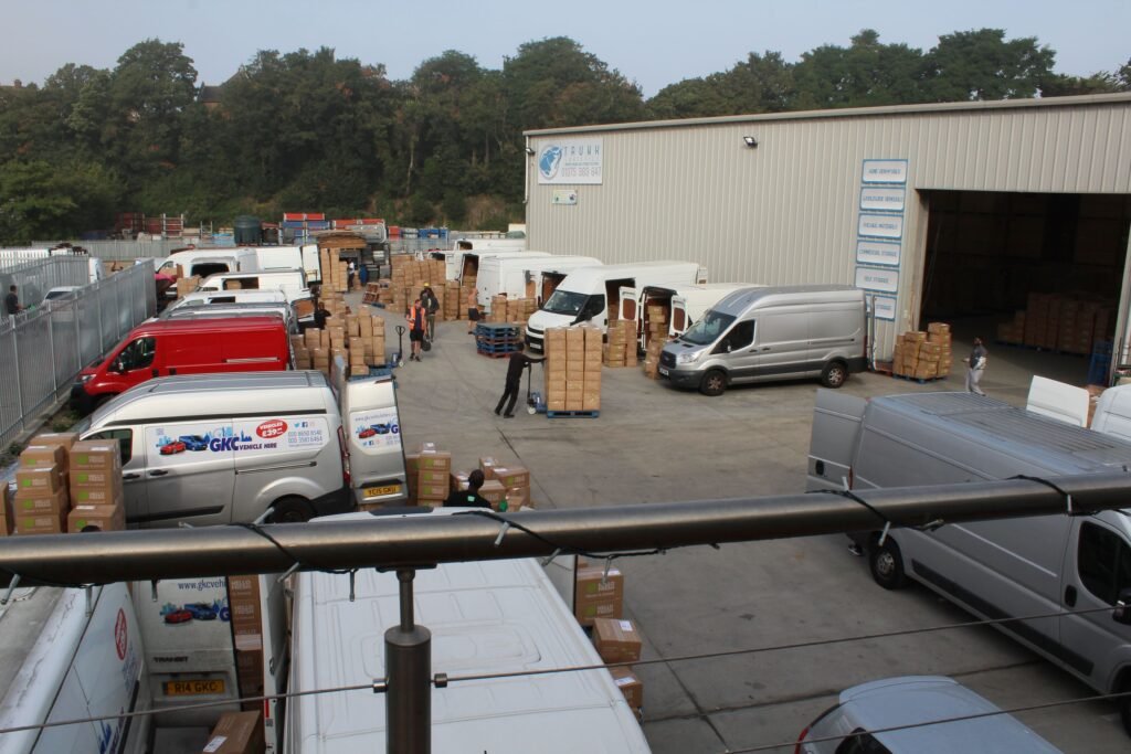 Warehousing and Logistics Aerial view of Trunk Logistics warehouse site in Grays Essex showing multiple courier vans collecting delivery boxes at loading bays