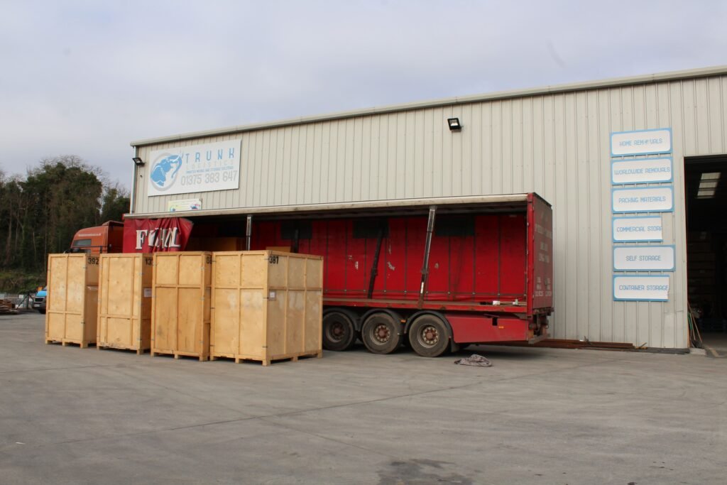Machinery Pre-Site Storage Trunk Logistics warehouse building in Grays Essex with HGV curtainsider trailer at loading bay and wooden storage crates in yard