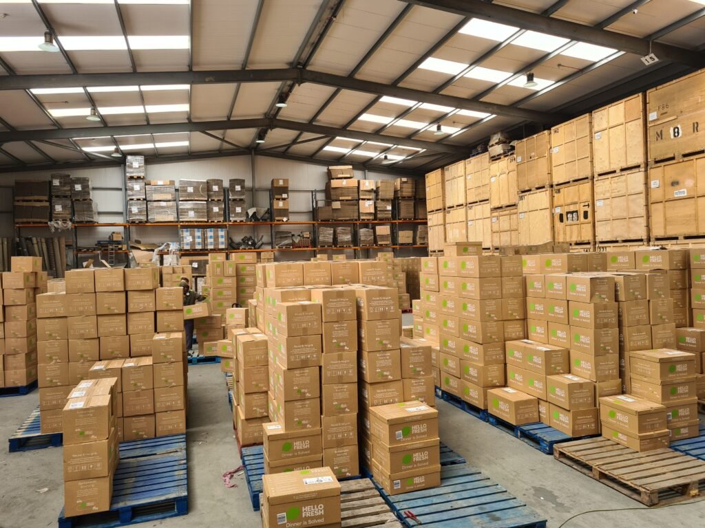 Overnight warehouse sortation operation at Trunk Logistics Grays Essex showing HelloFresh delivery boxes sorted by courier route on pallets