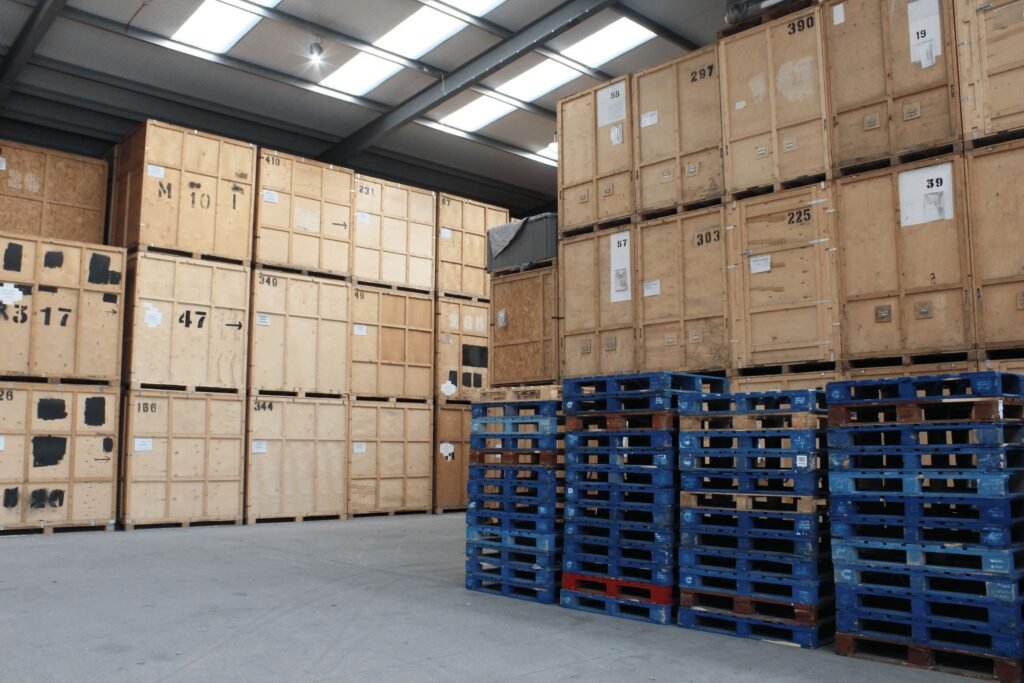 Commercial warehouse storage in Grays Essex showing numbered wooden storage crates stacked to roof height with blue pallets in foreground