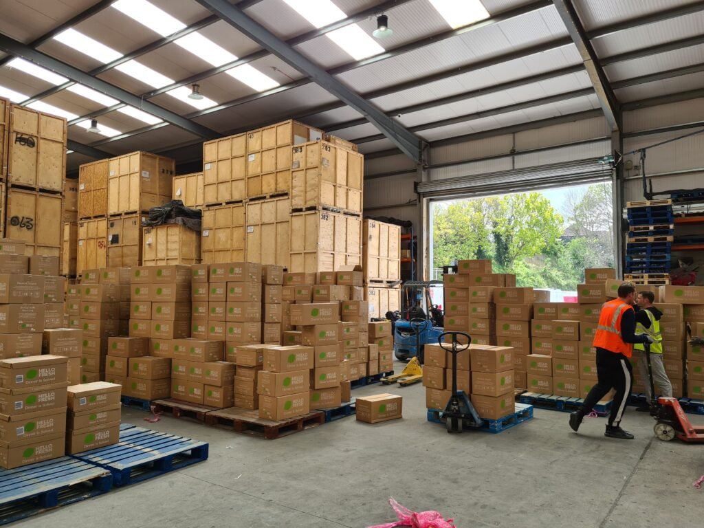 Satellite Warehouse and Southern Distribution Hub Two Trunk Logistics warehouse operatives using pallet jack during overnight sortation at Grays Essex warehouse with open loading bay