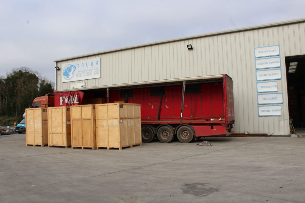 Container Devanning and Import Storage - London Gateway Trunk Logistics warehouse exterior in Grays Essex with large vehicle delivery at loading bay showing storage crates in yard