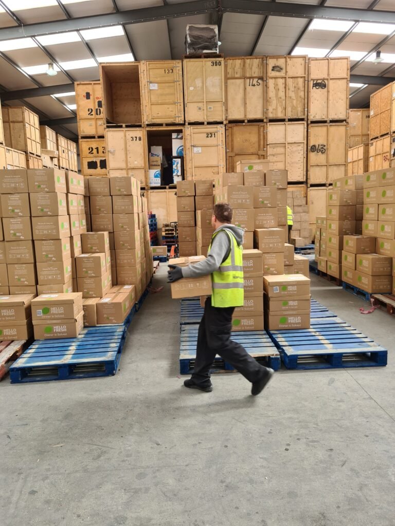 Overnight Food Box Sortation Trunk Logistics warehouse operative carrying delivery box during overnight sortation operation in Grays Essex